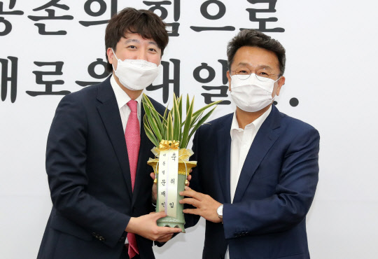 이준석 국민의힘 신임 대표(왼쪽)가 16일 서울 여의도 국회에서 이철희 청와대 정무수석의 예방을 받고 문재인 대통령의 축하난을 전달받고 있다. 연합뉴스.